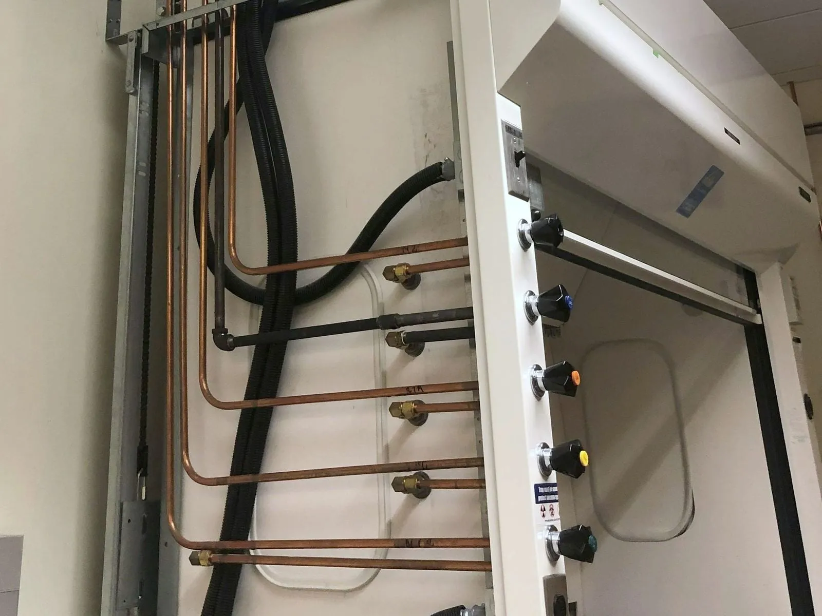 Copper lines bent into the service fittings on the side of a lab fume hood