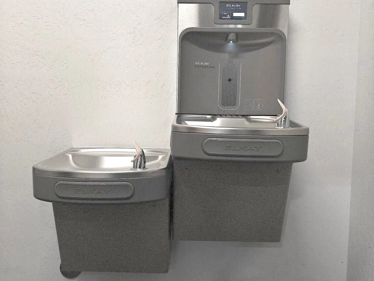 High-low drinking fountain with a bottle filler on a white wall
